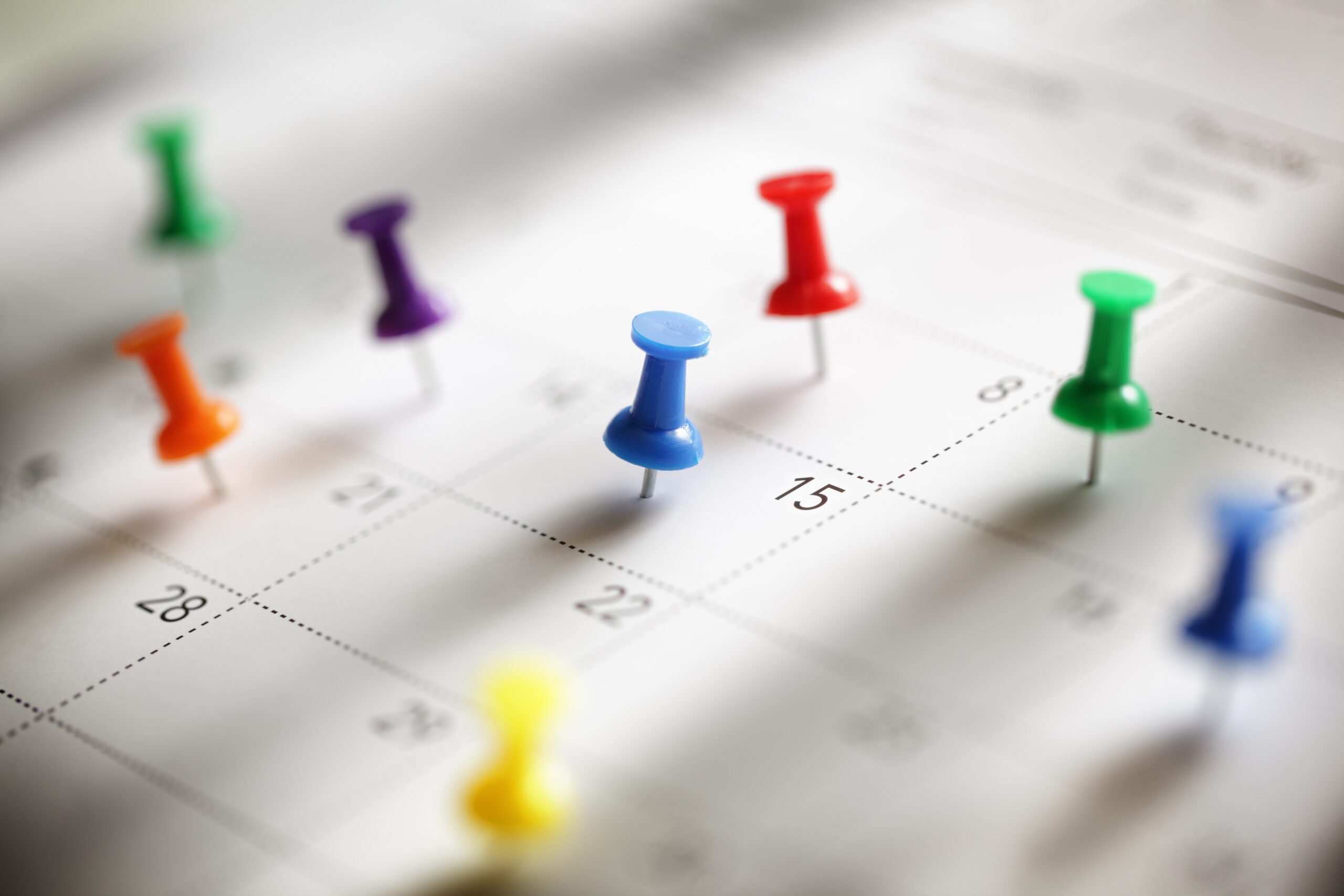 Image of a calendar with colorful push pins on it